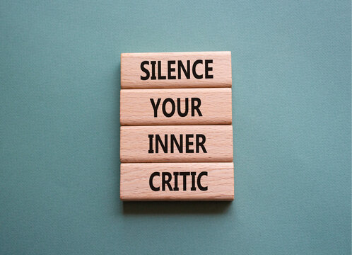 Silence your inner critic symbol. Wooden blocks with words Silence your inner critic. Beautiful grey green background. Businessman hand. Business and Silence your inner critic concept. Copy space.