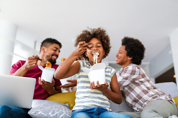 Happy african family eating at living room and enjoying time together. Home delivary takeaway food