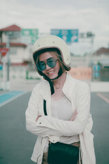 asian woman wearing white safety helmet standing on city road toothy smiling with happiness