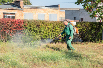 Worker sprays territory with insecticide for mosquitoes or pests or herbicides for weeds.