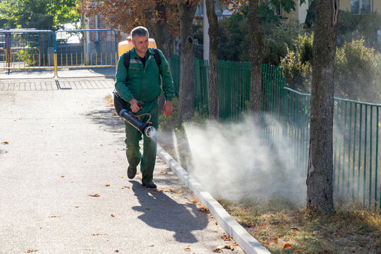Worker sprays territory with insecticide for mosquitoes or pests or herbicides for weeds.