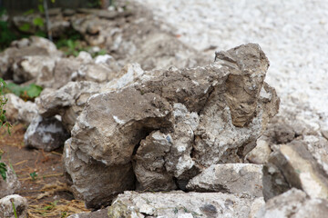 Construction, laying road on a new one. On side of the road lie blocks of large gray stones