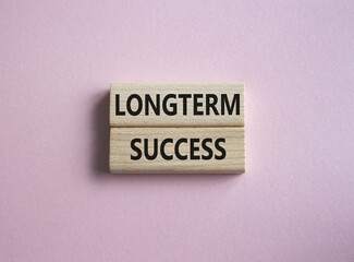 Longterm success symbol. Wooden blocks with words Longterm success. Beautiful pink background. Business and Longterm success concept. Copy space.