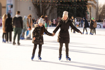 Mother with her daughters skates on ice skating