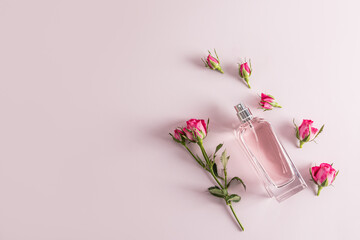 A beautiful bottle of women's perfume with a delicate aroma of roses on a pastel background among...