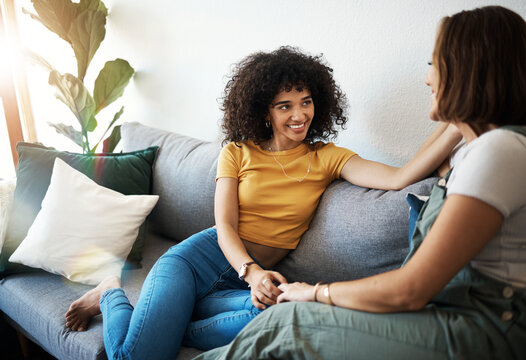 Discussion, love and lesbian couple relaxing on a sofa in the living room talking and bonding. Happy, conversation and young interracial lgbtq women speaking and resting together in lounge at home