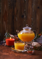 Fototapeta na wymiar Glass teapot and sea buckthorn tea cup on wooden background