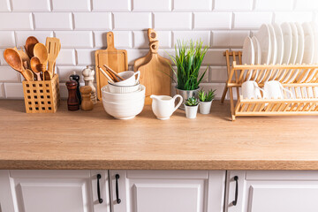 Beautiful kitchen background with different items and kitchen utensils made of eco-friendly materials. wooden countertop, white brick wall.