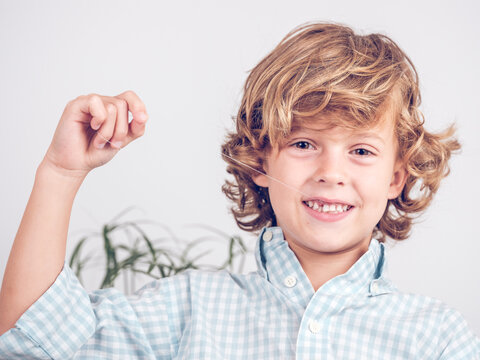 Cheerful preteen boy pulling tooth with thread