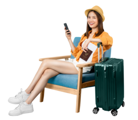 Happy Asian woman traveler sitting on the chair and using smartphone with holding passport and plane tickets with suitcase isolated on blue background.