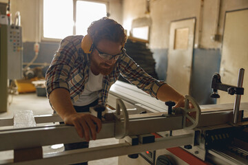 Professional carpenter cutting wooden board at sawmill carpentry manufacturing . Sawing machine