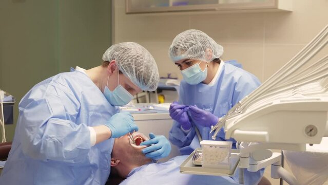 dentist and assistant suturing patient's gum
