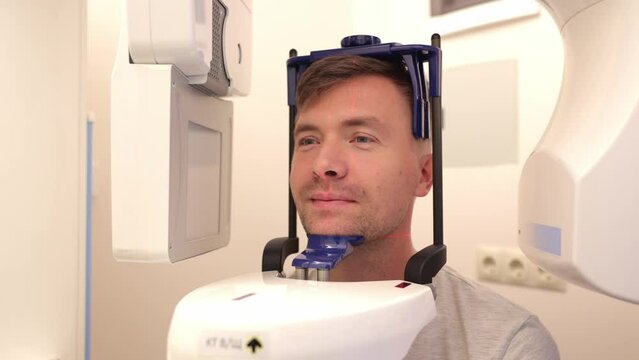 Dental x-ray machine with a cephalometric socket, an man takes a picture of his face.