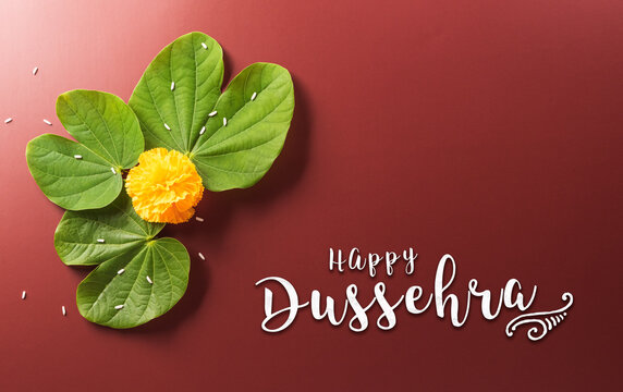 Happy Dussehra. Yellow flowers, green leaf and rice on dark paper background. Dussehra Indian Festival concept.