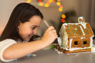 Little girl decorating gingerbread house for Christmas