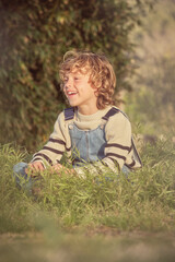 Naklejka na ściany i meble Little smiling boy sitting on grass