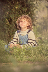 Boy sitting on grass on sunny day