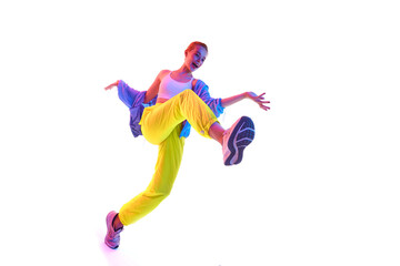 Fototapeta na wymiar From below full body of happy young woman training, dancing in trendy sport outfit and sneakers looking at camera in neon light.