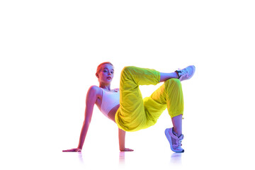 Full length portrait of young girl do Glute Stretches for tailbone stung with bridge pose and cross legs in fashion sport outfit and headphones in neon light. - obrazy, fototapety, plakaty