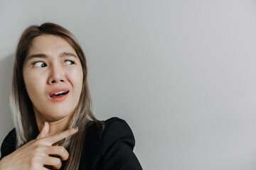 Asian Thai office woman funny dislike face, pointing fingers at empty space, isolated on white...