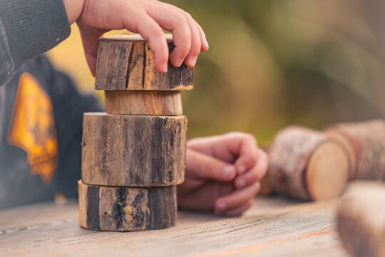Toddlers hands building tower with natural wooden blocks at preschool