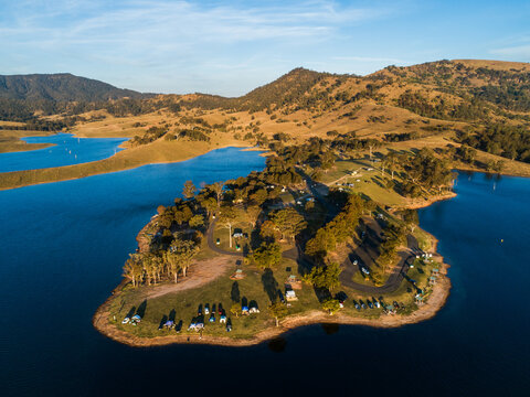 Campsite and campgrounds on headland jutting into blue water of water catchment lake