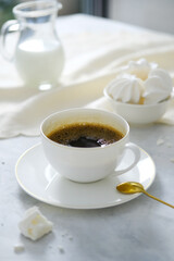 A mug of coffee with a white, bright interior. A mug of coffee on the dining table with desserts