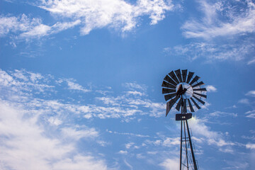 Old metal windmill with blue sky background - Powered by Adobe
