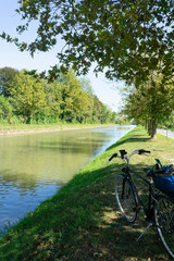 Bicycle parked in the tree-lined bank of a river during an ecological excursion in the Riviera del Brenta province of Venice