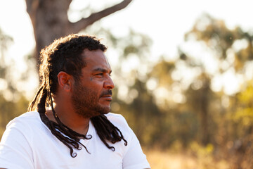 Side profile portrait of aboriginal man looking away with dreadlocks and neutral expression