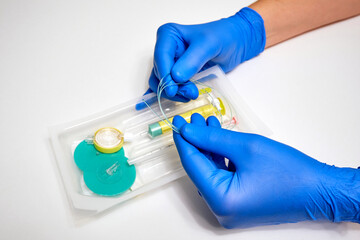 Epidural anesthesia kit and medic's hands in blue protective gloves close-up