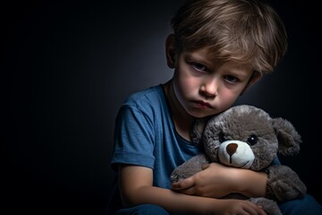 A sad young boy cherishes his beloved teddy bear