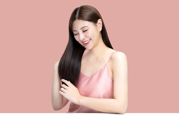 Portrait beauty Asian woman with K-beauty make up showing shining hair isolated on pink background.