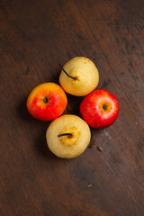 red pears and apples on a wooden base, in the photo from above