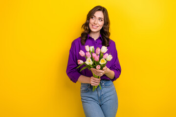 Photo of gorgeous minded lady hold fresh tulip flowers look empty space ad isolated on yellow color background