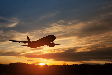 Airplane taking off at the sunset sky. Silhouette of aircraft in the sky.