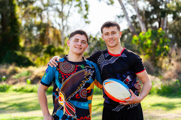 Aboriginal cousins on the edge of sports ground holding football