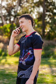 Happy aboriginal teenager in sports polo talking on mobile phone