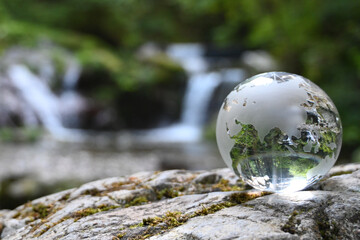 ガラスの地球儀と美しい渓流　地球環境に関するイメージ　Glass globe and beautiful waterfall	