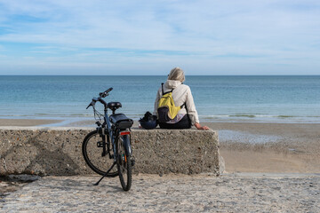 Femme contemplant la mer, en pause aves son vélo électrique