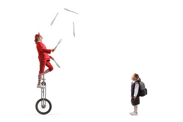Surprised schoolgirl watching an acrobat riding a giraffe unicycle and juggling