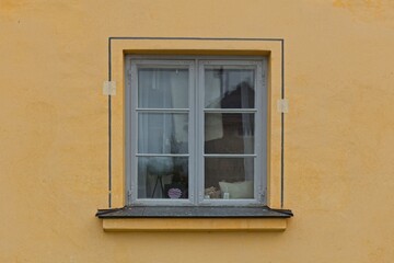 Fototapeta na wymiar Window with frame painted grey on a yellow stone wall.