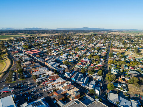 Aerial view of sunlit town with shops along main street and rows of houses down streets