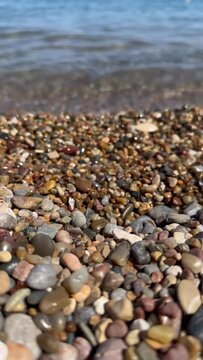 Sea waves and pebbles coast. Rocky beach pebbles on shore and rolling sea waves splashing. Vertical