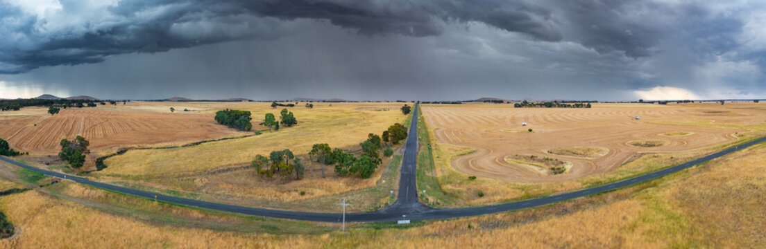 Heavy rain and dark cloud over dry farmland around a rural T intersection