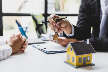Real estate agents agree to buy a home and give keys to clients after signing contract agreement in office, moving home or renting property.