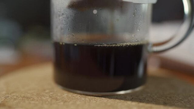 Black coffee dropping into a glass jug