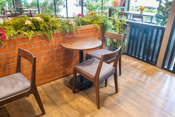 Wooden chairs and tables with green forest wall,flower and red brick wall in Relax restaurant or cafe.