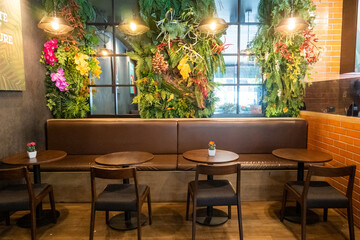 Wooden chairs and tables with green forest wall at night bar or restaurant,modern cafe at night.