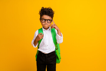 Portrait of smart minded boy with wavy hairdo wear stylish shirt touch glasses look empty space isolated on yellow color background